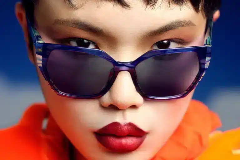 Portrait d'une femme portant des lunettes de soleil modernes de la collection SS25 d'Etnia Barcelona, monture bleu translucide.