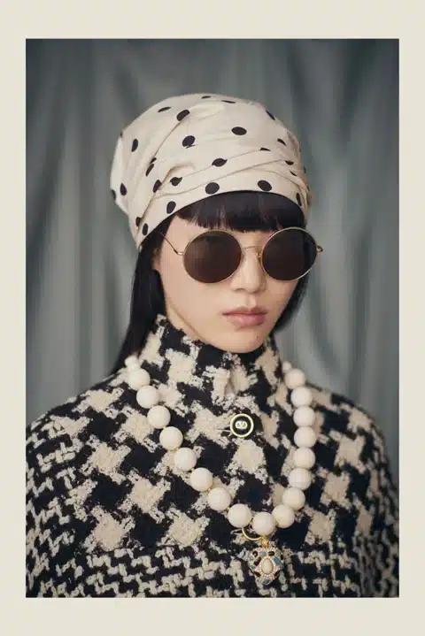Parisee - Modèle portant des lunettes de soleil rondes Valentino de la collection "Avant les Débuts", avec un look rétro chic inspiré de la haute couture.