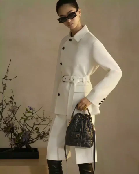Lunettes de soleil Dior 2025 portées par une femme en tenue blanche, avec sac cannage noir et design couture